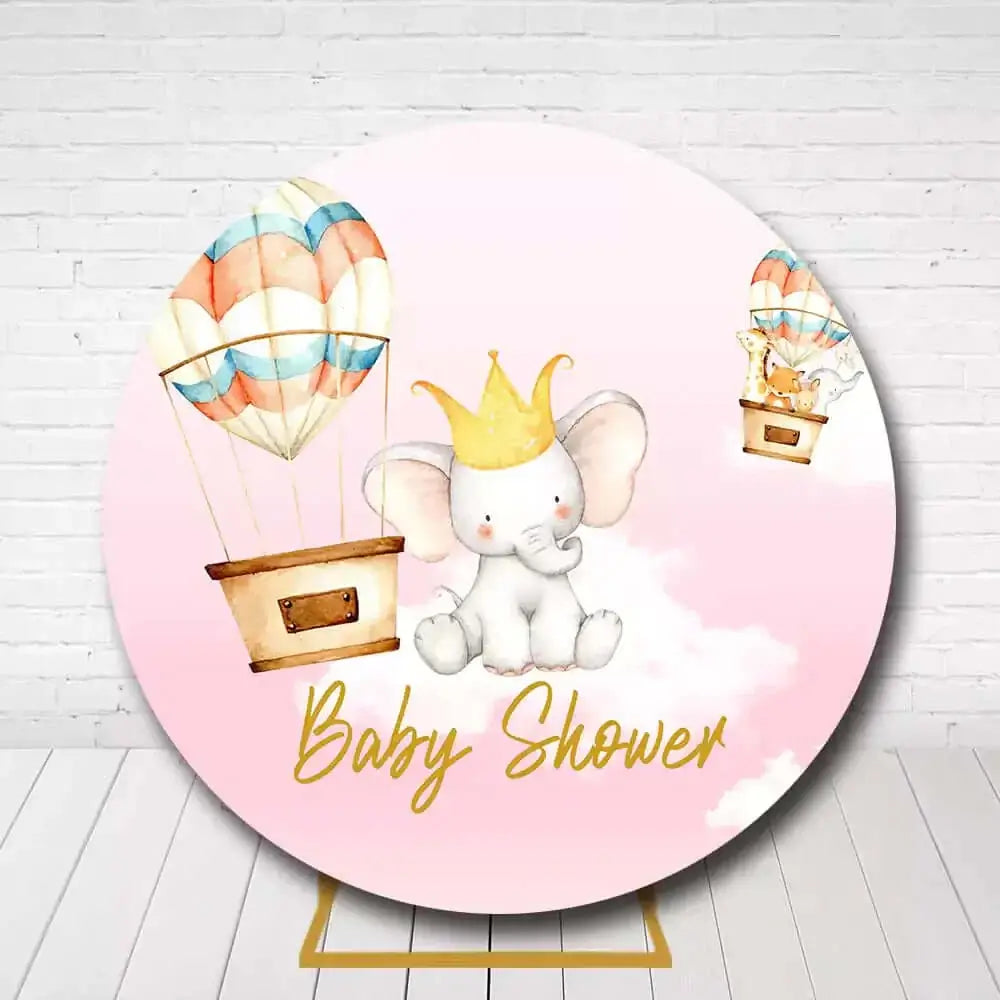 Round baby shower backdrop with pink background, elephant wearing crown, and hot air balloons