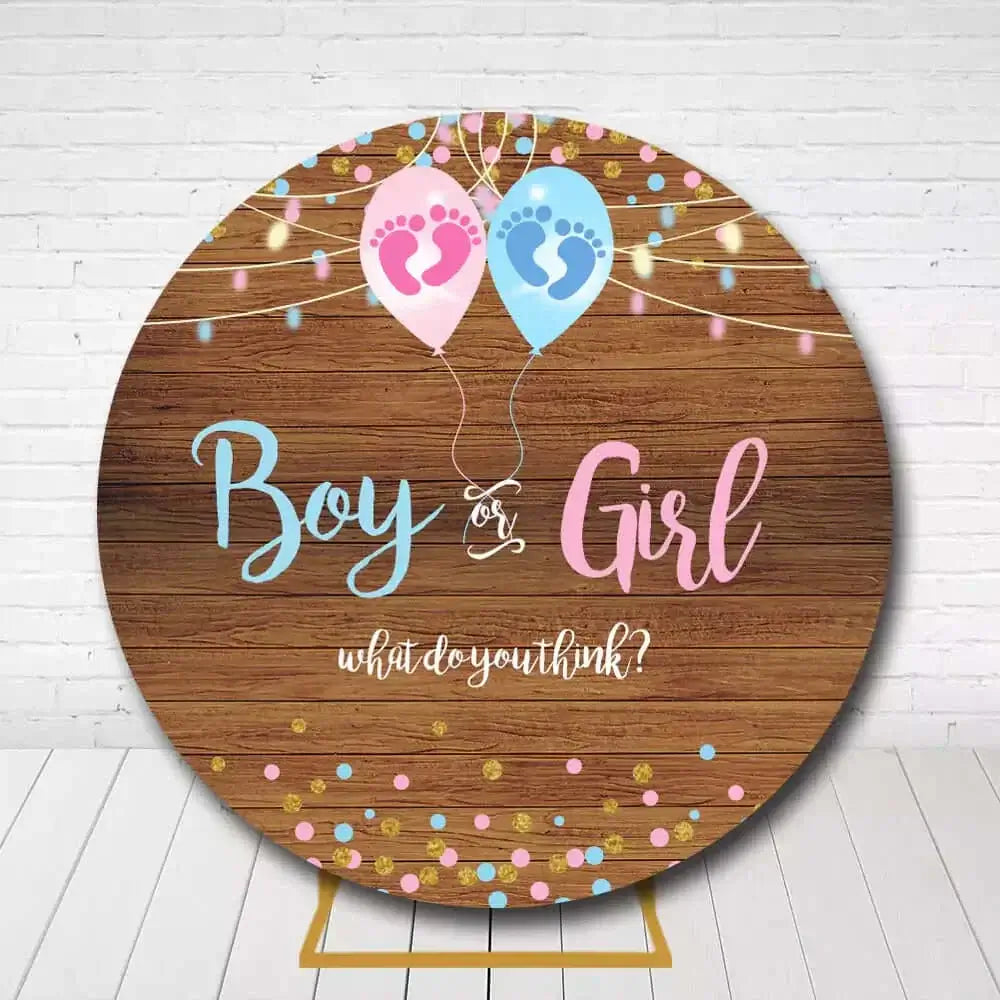 Round rustic gender reveal backdrop with wooden design, blue and pink balloons, and baby footprints
