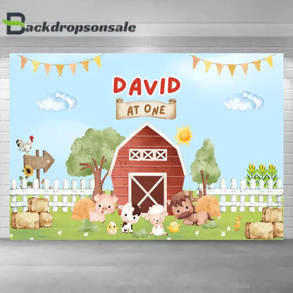 Farm-themed first birthday backdrop with red barn, animals, and hay bales for party decoration