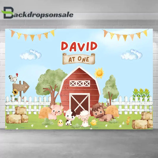 Farm-themed first birthday backdrop with red barn, animals, and hay bales for party decoration