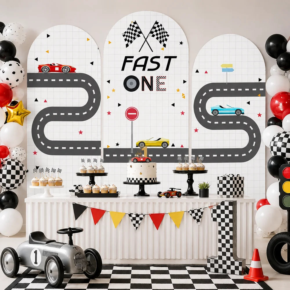 Fast One racing first birthday set with three arch backdrop covers featuring race cars, winding road tracks, checkered flags and colorful racing details.