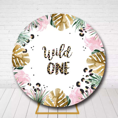 Tropical jungle circle backdrop with gold monstera leaves and Wild One lettering for first birthday
