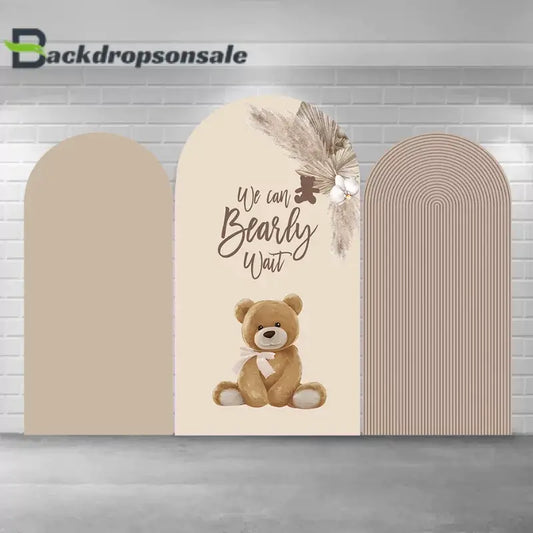 Neutral-toned teddy bear baby shower arch backdrop set with three panels featuring beige stripes, a cute teddy bear illustration, the text "We Can Bearly Wait," and floral arrangements.