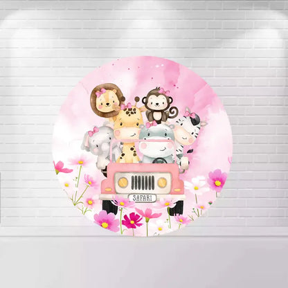 A round safari-themed backdrop with adorable animals—giraffe, monkey, zebra, lion, and elephant—riding in a pink jeep with pink flowers and watercolor details.