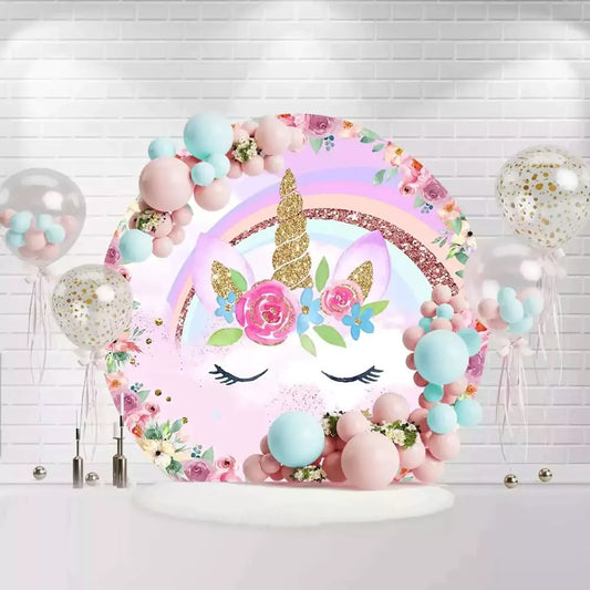 Pink unicorn round backdrop with gold horn, rainbow, and floral decorations for birthday party