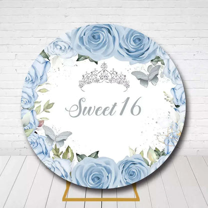 Sweet 16 round backdrop with blue roses, crown, and butterflies for birthday party