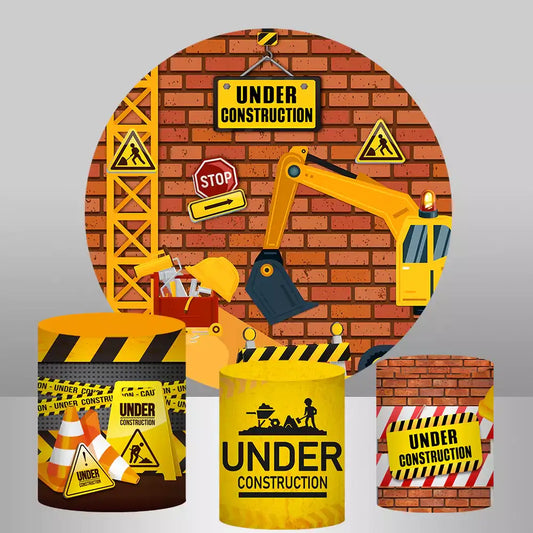 An under-construction-themed party decor set featuring a round backdrop with construction vehicles and three matching cylinder covers with caution tape, cones, and brick wall designs.