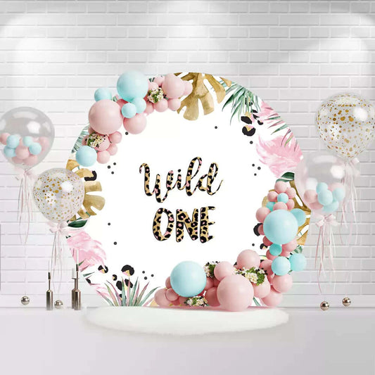 Round Wild One backdrop with leopard print text, tropical leaves, and pink flowers